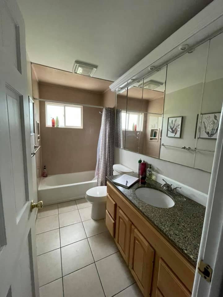 Bathroom before remodel, dated tan tile and oak vanity